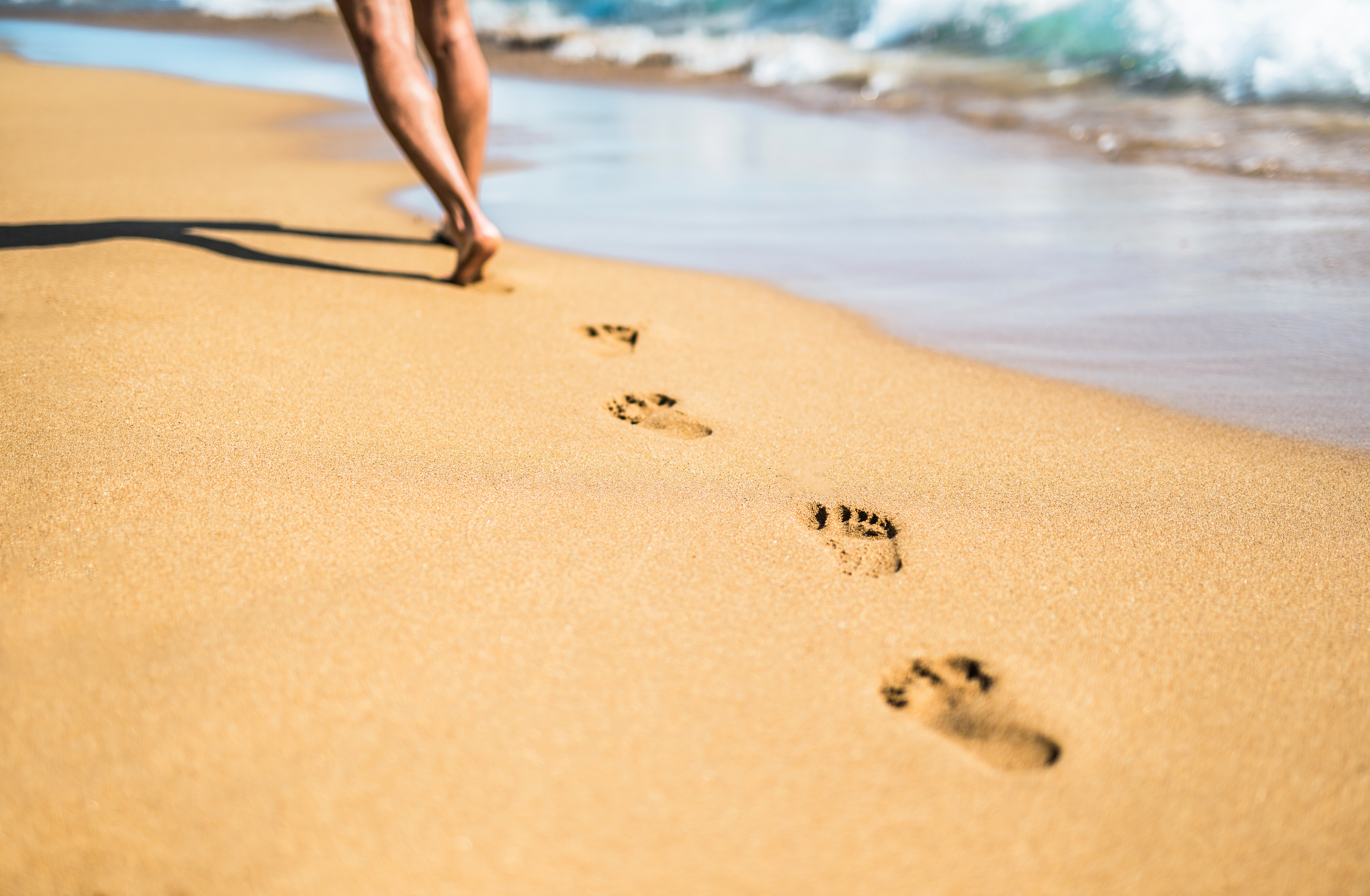 Young man leaving foot steps in the sand